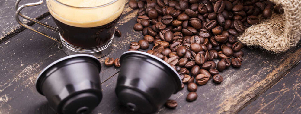 Cafea Baque în capsule compatibile, alături de boabe de cafea și o ceașcă preparată